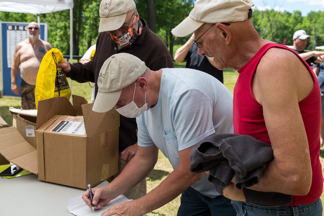 Man signing in at the CreekRidge campground registration table during check-in while other guests wait nearby.