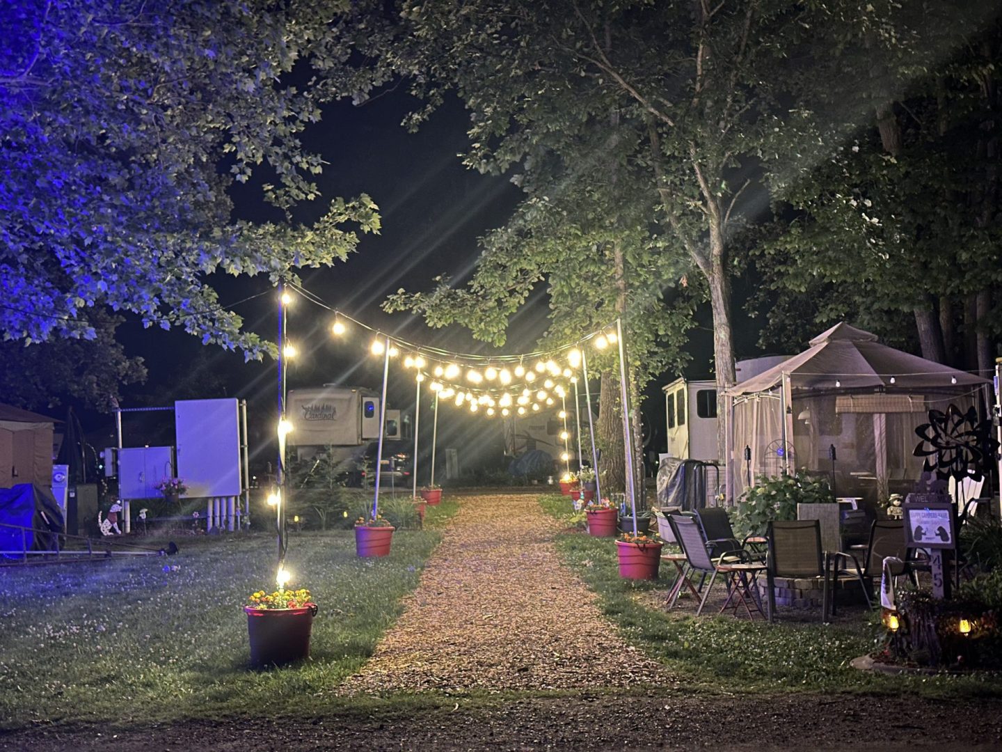 Decorative string lights along a campground pathway between RV campsites.