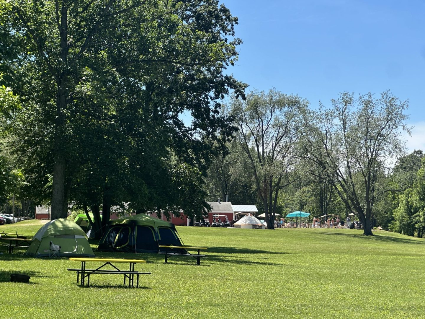 Spacious tent camping area at CreekRidge Campground with shaded campsites and open grassy field.